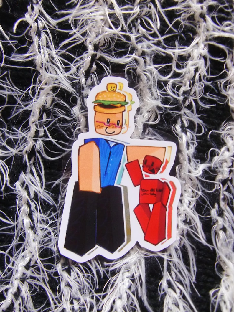 Puede incluir: Una pegatina con un personaje de dibujos animados con cabeza de hamburguesa, sosteniendo una figura de bloque rojo. El personaje lleva una camisa azul y pantalones negros. La figura roja tiene texto. Fondo texturizado en blanco y negro.