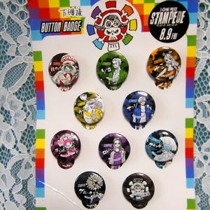 May include: A collection of nine round button badges featuring characters from the anime series "One Piece". The badges are on a white card with a rainbow border and the text "BUTTON BADGE". Each badge has a different character design.