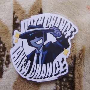 Puede incluir: Una pegatina con un personaje de dibujos animados con traje y sombrero, con el texto "TAKE A CHANCE" en una fuente estilizada. El personaje es azul con fondo blanco y estrellas amarillas.