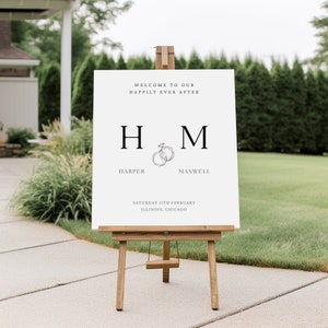 Könnte beinhalten: Weißes Hochzeitsschild mit schwarzem Text. Das Schild lautet "Willkommen in unserem Happy End" mit den Initialen des Paares "H & M" und den Namen "Harper & Maxwell". Das Schild enthält auch das Datum "Samstag, 11. Februar" und den Ort "Illinois, Chicago".