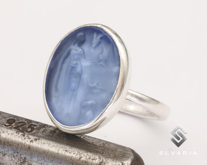May include: A silver ring with a blue cameo featuring a woman's profile and a floral design.