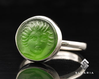 May include: A silver ring with a green glass cameo featuring a detailed profile of a woman's face.