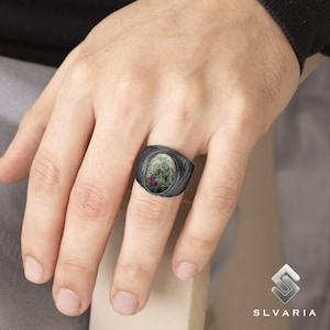 May include: A silver ring with a black oxidised finish and a green and pink oval gemstone.