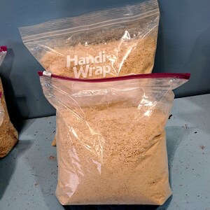 Puede incluir: Dos bolsas de pl&aacute;stico transparente llenas de material granular de color marr&oacute;n claro. Las bolsas est&aacute;n selladas con un cierre de cremallera rojo. Una bolsa est&aacute; apilada encima de otra. La bolsa superior tiene la inscripci&oacute;n "Handi Wrap".