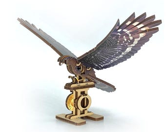 May include: A wooden 3D puzzle of a hawk with outstretched wings. The hawk is brown with detailed wing patterns in shades of brown, gray, and white. It is mounted on a wooden stand with the word "TAIWAN" visible. The puzzle is designed for assembly.