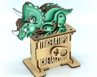 May include: A wooden Triceratops dinosaur model in shades of green and brown, mounted on a wooden stand. The stand features the words "TRICERATOPS" and "CRETACEOUS" in a bold font. The dinosaur has three horns and a frill.
