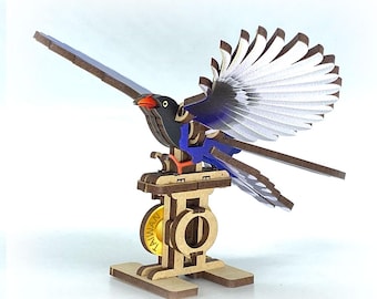 May include: A wooden bird model with outstretched wings, featuring black, blue, and white feathers, and a red beak. The bird is mounted on a wooden base with a gold-colored wheel that has the word "TAIWAN" on it. The model is designed to appear as if the bird is in flight.