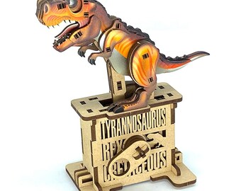 May include: A wooden Tyrannosaurus Rex dinosaur puzzle with orange and brown coloring. The dinosaur is standing on a wooden base with the words "TYRANNOSAURUS REX" and "RED" cut out. The dinosaur has an open mouth.