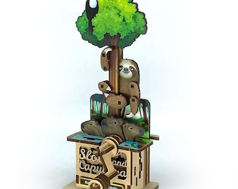 May include: A wooden, laser-cut kinetic sculpture featuring a sloth, toucan, and capybaras. The tree-themed design includes a toucan perched in the green foliage, a sloth clinging to the trunk, and capybaras below. The base has the text "Slow Capy and Ra...mals".