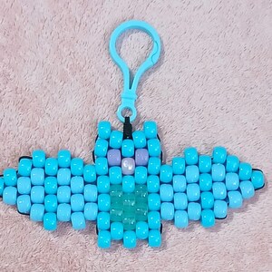 Light blue aethetic Kandi Bat with a light blue body, pastel blue wings, UV reactive transparent light blue belly, light pearly pink nose, and lavendar eyes, done on black stretchy cord and finished with a light blue hook.