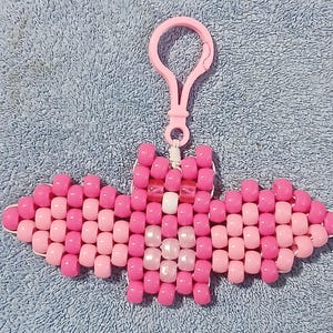 Valentines Pink aethetic Kandi Bat with a pink body, light pink wings, pearly light pink belly, white nose, UV reactive pink eyes, and done on white stretchy cord finished with a light pink hook.