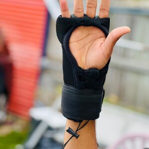 K&ouml;nnte beinhalten: Schwarzer gepolsterter Trainingshandschuh mit Mesh-Design und verstellbarem Handgelenkband. Der Handschuh hat einen Klettverschluss.