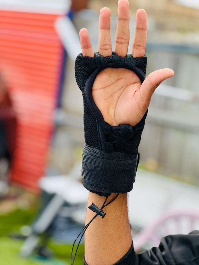 K&ouml;nnte beinhalten: Schwarzer gepolsterter Trainingshandschuh mit Mesh-Design und verstellbarem Handgelenkband. Der Handschuh hat einen Klettverschluss.