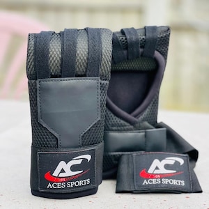 May include: A pair of black wrist wraps with a mesh design and a black strap with the text "ACES SPORTS" in red and white.