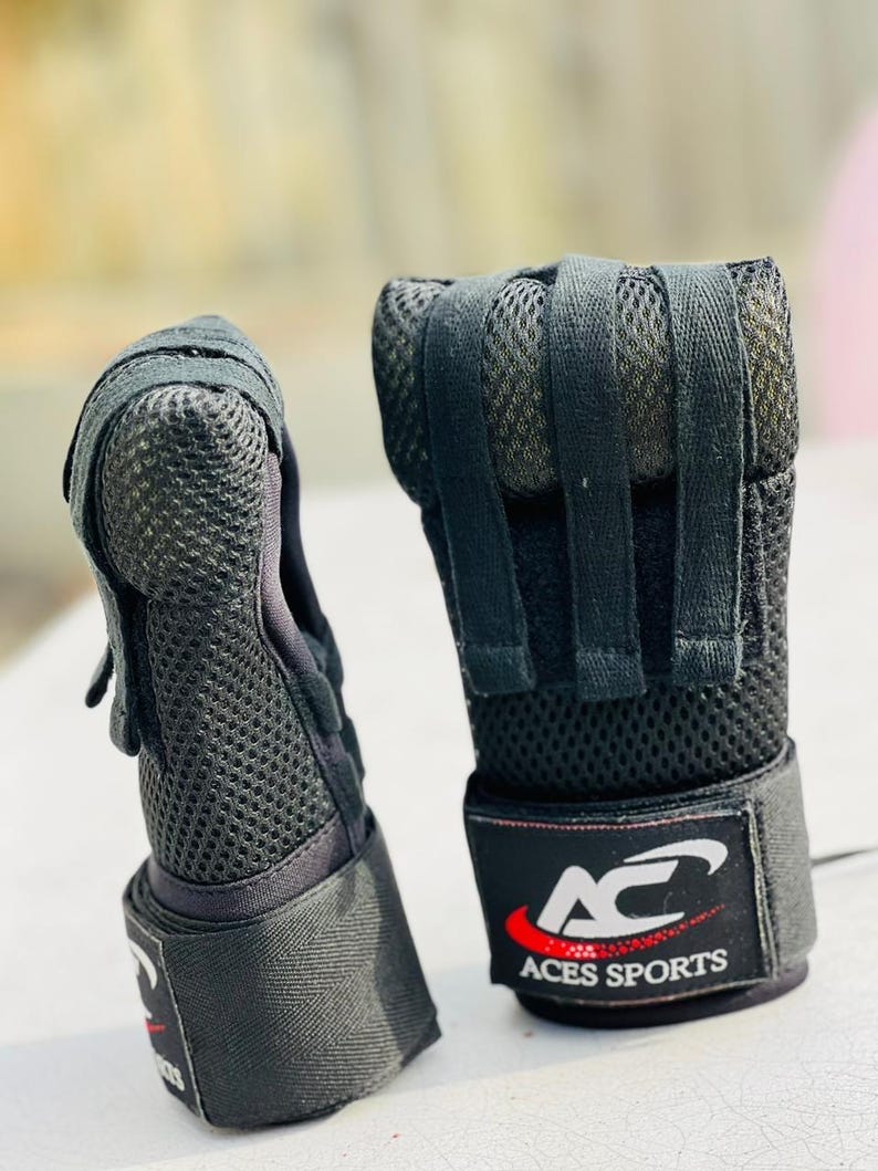 K&ouml;nnte beinhalten: Ein Paar schwarze fingerlose Trainingshandschuhe mit atmungsaktivem Mesh-Design und verstellbaren Handgelenksriemen. Die Handschuhe haben das Logo "AC Aces Sports" auf dem Handgelenksriemen.