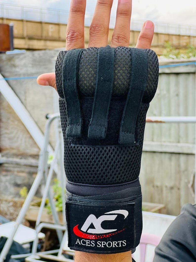 K&ouml;nnte beinhalten: Schwarze Handgelenksbandagen mit einem Mesh-Panel und einem Klettverschluss. Die Bandagen haben einen gepolsterten Bereich zum Schutz. Das Markenlogo ist "Aces Sports" in wei&szlig;er Schrift auf schwarzem Hintergrund mit einem roten Schwung.