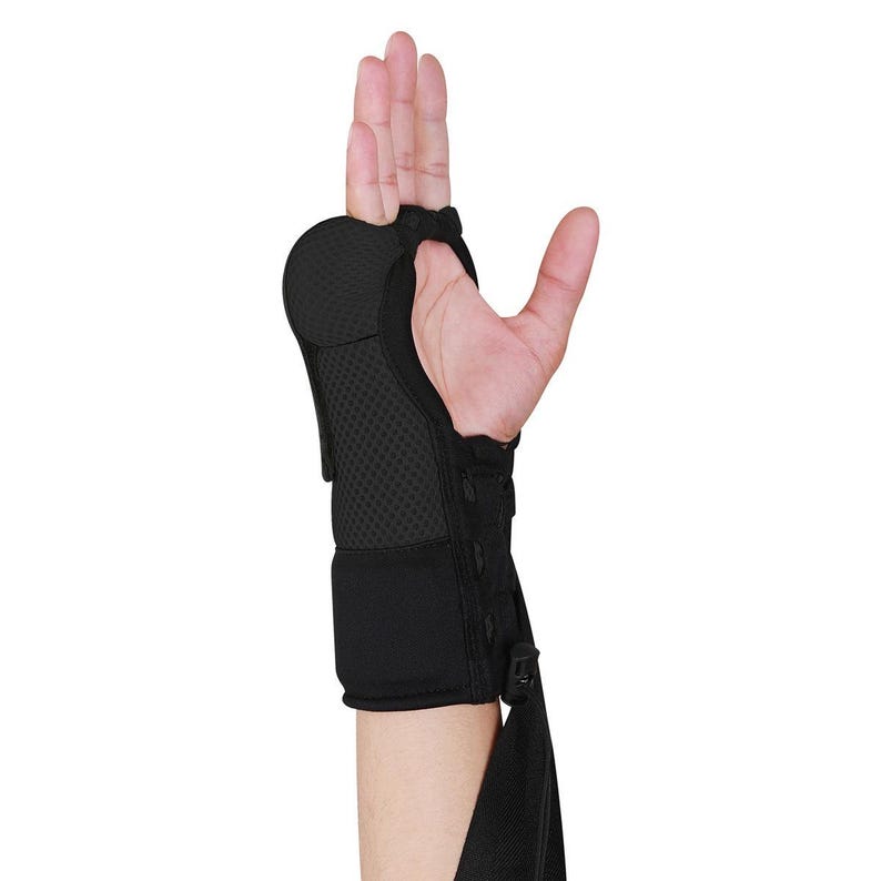 K&ouml;nnte beinhalten: Schwarze Handgelenkst&uuml;tze mit verstellbaren Riemen und einer gepolsterten Handfl&auml;che. Die St&uuml;tze besteht aus atmungsaktivem, flexiblem Material.