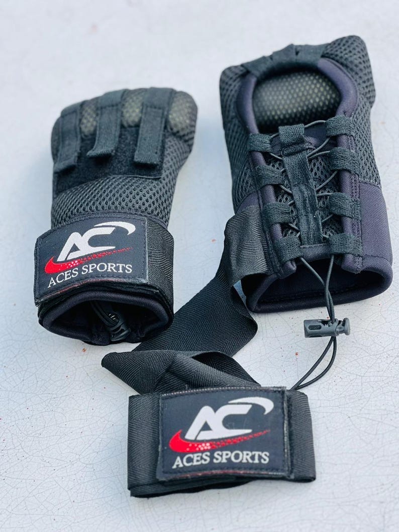 K&ouml;nnte beinhalten: Ein Paar schwarze Handgelenksbandagen mit einem schwarzen Netzdesign und einem roten und wei&szlig;en Logo mit der Aufschrift "Aces Sports".