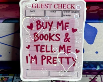 May include: A pink and white sticker resembling a guest check, featuring the text "BUY ME BOOKS & TELL ME I'M PRETTY" in pink, with heart motifs. The top of the sticker reads "GUEST CHECK".