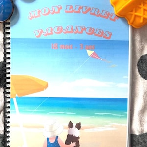 May include: A spiral-bound children's book with the title "MON LIVRET VACANCES" and the age range "18 mois - 3 ans". The cover features a beach scene with a child, a dog, and a kite. Sunglasses and a toy ice cream cone are on top.
