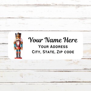 May include: White rectangular label with a colorful illustration of a nutcracker soldier. The label includes the text "Your Name Here", "Your Address", and "City, State, Zip Code". The background is a white wooden surface.