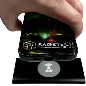 May include: A black wireless charger with a silver charging symbol is shown with a smartphone on top. The phone displays the "SAGETECH" logo and a green and red graphic. The phone is held by a hand.