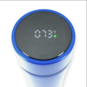 May include: Close-up of a digital thermometer with a blue rim. The display shows the number "073:" in white digits, with a small green dot to the right. The device has a white body.