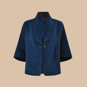 May include: A dark blue jacket with a mandarin collar and a decorative button closure. The jacket has a textured fabric and a slightly cropped length.