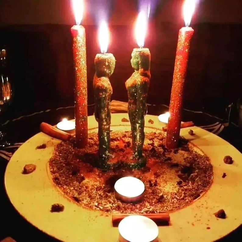 May include: A spiritual arrangement featuring four lit candles. Two green figure candles stand between two red pillar candles, all on a yellow plate with herbs and spices. Several small white candles and cinnamon sticks are also present, creating a mystical ambiance.