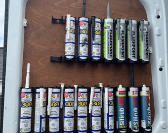 May include: A close-up of a wall mounted organizer with various tubes of sealant and adhesive. The tubes are labeled with brand names such as "FLASHPOINT", "CT1", and "Silirub".