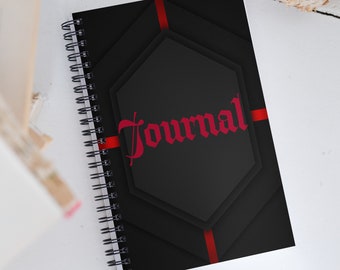 Könnte beinhalten: Schwarzes spiralgebundenes Notizbuch mit einem roten und schwarzen geometrischen Design. Das Wort "Journal" ist in rot auf dem Einband geschrieben.