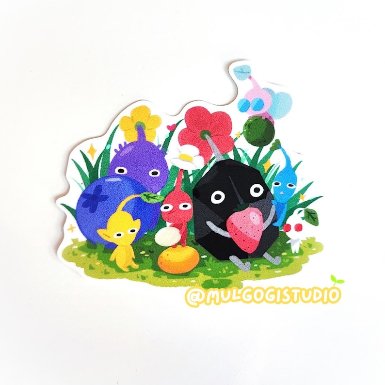 Op de afbeelding: Een sticker met een groep kleurrijke cartoonfiguren, waaronder een zwart personage met een aardbei, een paars personage met een bosbes, een geel personage met een blad en een rood personage met een sinaasappel. De personages zijn omringd door bloemen en gras. De sticker bevat de tekst "@MULCOGISTUDIO".