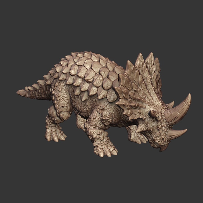 May include: A light brown, detailed dinosaur figurine featuring a heavily armored back with large, overlapping scales and a prominent frill. The creature has two distinct horns on its snout and a textured, rugged skin appearance throughout its body.