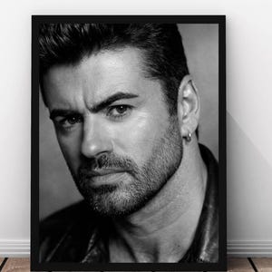 May include: Black and white framed portrait of a man with short, dark hair and a trimmed beard. The portrait is a close-up of the man's face, with a serious expression. He wears a small hoop earring. The frame is black.