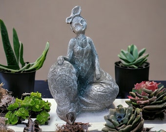 Moderne Skulptur einer sitzenden Frau mit Pumphose und Schleife im Haar (Maße: 21/16/8 cm)