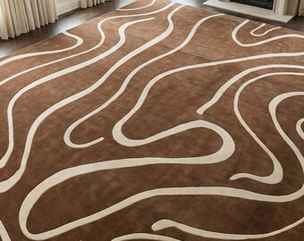 Può includere: Un grande tappeto marrone con un design astratto e fluido color crema. Il tappeto si trova in una stanza spaziosa con grandi finestre e un camino. Il design del tappeto aggiunge un tocco moderno all'arredamento della stanza.