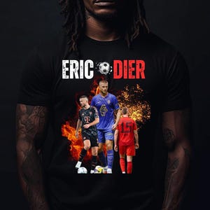 Puede incluir: Camiseta negra con el nombre "ERIC DIER" en blanco y rojo, y un gráfico de balón de fútbol. La camiseta muestra imágenes de futbolistas con llamas de fondo. La persona que lleva la camiseta tiene rastas.
