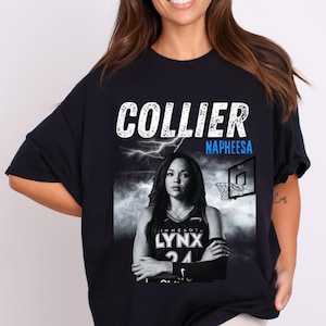 May include: Black t-shirt featuring a portrait of Napheesa Collier, a basketball player, with the text "COLLIER" above her image. The text "MINNESOTA LYNX 24" is also visible. A basketball hoop and lightning are in the background.