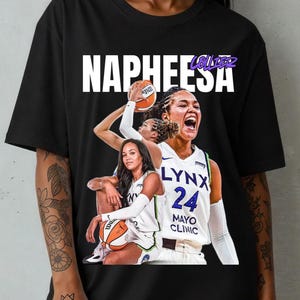 Pode incluir: Camiseta preta com o nome "NAPHEESA" em letras brancas. A camiseta exibe uma colagem de uma jogadora de basquete com o uniforme do Lynx, com o número 24. O nome da equipe e o logotipo da Mayo Clinic também são visíveis.