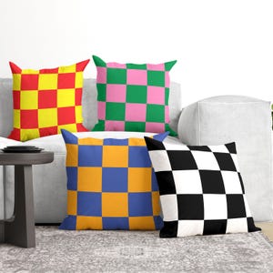 a collection of colorful throw pillows on a couch, with a gray rug on the floor in front of it.