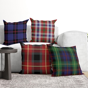 May include: Four square throw pillows featuring distinct plaid patterns. One pillow has a blue and black grid, another a red, green, and white tartan, a third a red, black, and yellow check, and the fourth a green, blue, and black tartan design.