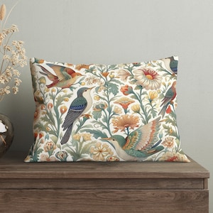 May include: A white throw pillow with a colorful floral and bird pattern. The birds are blue, green, red, and yellow. The flowers are red, yellow, and white.