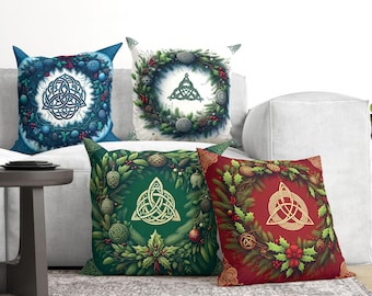 May include: Four square throw pillows featuring a central triquetra knot symbol surrounded by a circular wreath of pine branches, holly leaves, red berries, and decorative ornaments, presented in blue, white, green, and red color variations.