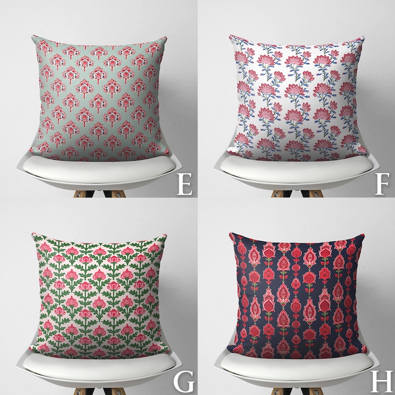 Puede incluir: Cuatro cojines decorativos con diferentes patrones florales. Los cojines son rojos, rosas, azules y verdes sobre un fondo blanco. Los cojines est&aacute;n en sillas blancas con patas de madera.