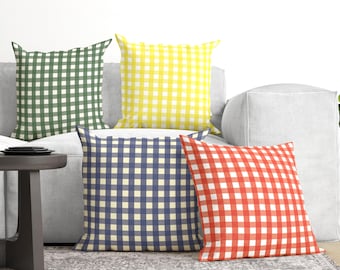 May include: Four square throw pillows featuring a classic gingham check pattern. The set includes one dark green, one bright yellow, one navy blue, and one vibrant red pillow, each displaying a consistent grid design across the entire surface.