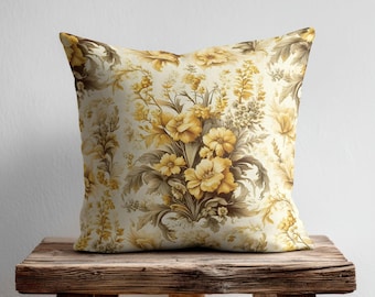 Può includere: Un cuscino quadrato con un motivo botanico ripetuto di fiori, foglie e steli nei toni del giallo e del marrone dorato su uno sfondo color crema. Il design presenta una fitta disposizione di motivi floreali su tutto il tessuto.