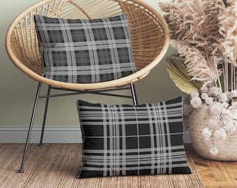 May include: Two square and rectangular throw pillows featuring a black and gray plaid pattern. The pillows have a consistent tartan design with intersecting lines of varying thickness, creating a classic grid motif across the fabric surfaces.