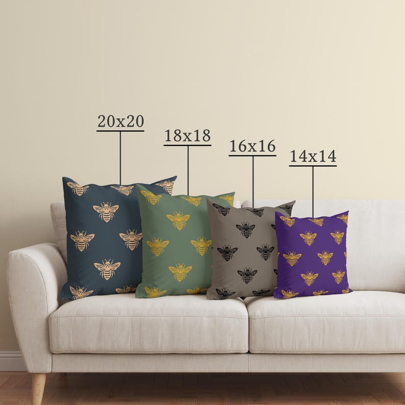 Puede incluir: Cuatro cojines decorativos con dise&ntilde;os de abejas en azul marino, verde, gris y morado. Tama&ntilde;os: 50x50, 45x45, 40x40 y 35x35 cm. Los cojines est&aacute;n colocados en un sof&aacute; blanco.