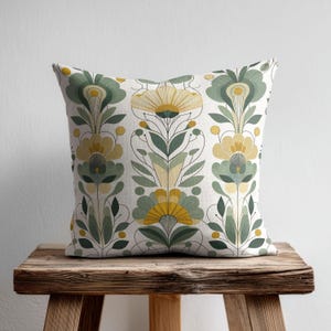 May include: A square throw pillow featuring a repeating vertical pattern of stylised flowers and leaves in shades of sage green, mustard yellow, and cream. The design consists of symmetrical botanical motifs with thin black outlines.