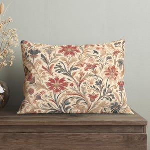 May include: A decorative throw pillow with a floral pattern featuring red, blue, and beige flowers on a cream background.